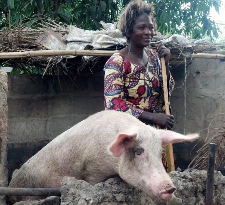 Éleveuse SANSA BITWISI avec son porc dans l’enclos