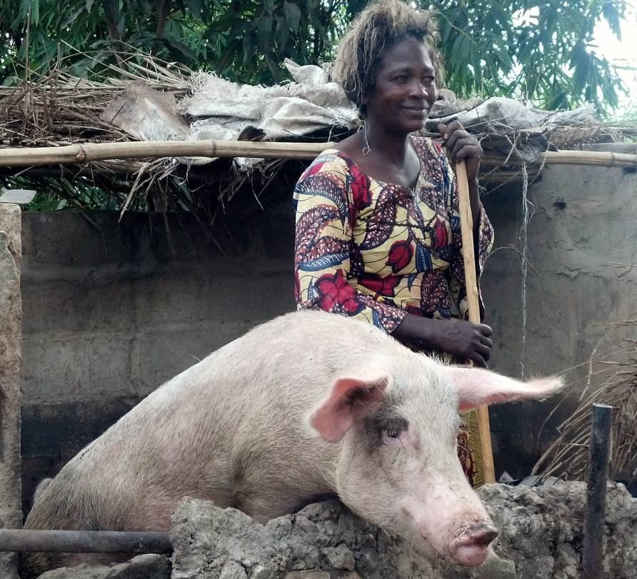 Éleveuse SANSA BITWISI avec son porc dans l’enclos